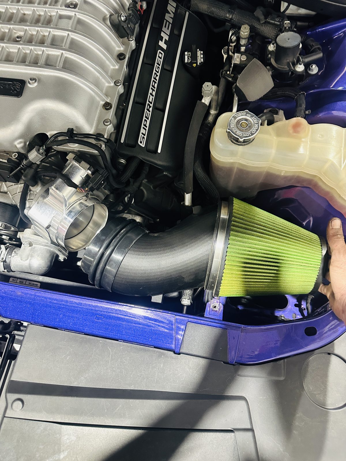 Alternate angle of a green cone filter intake in a blue engine bay