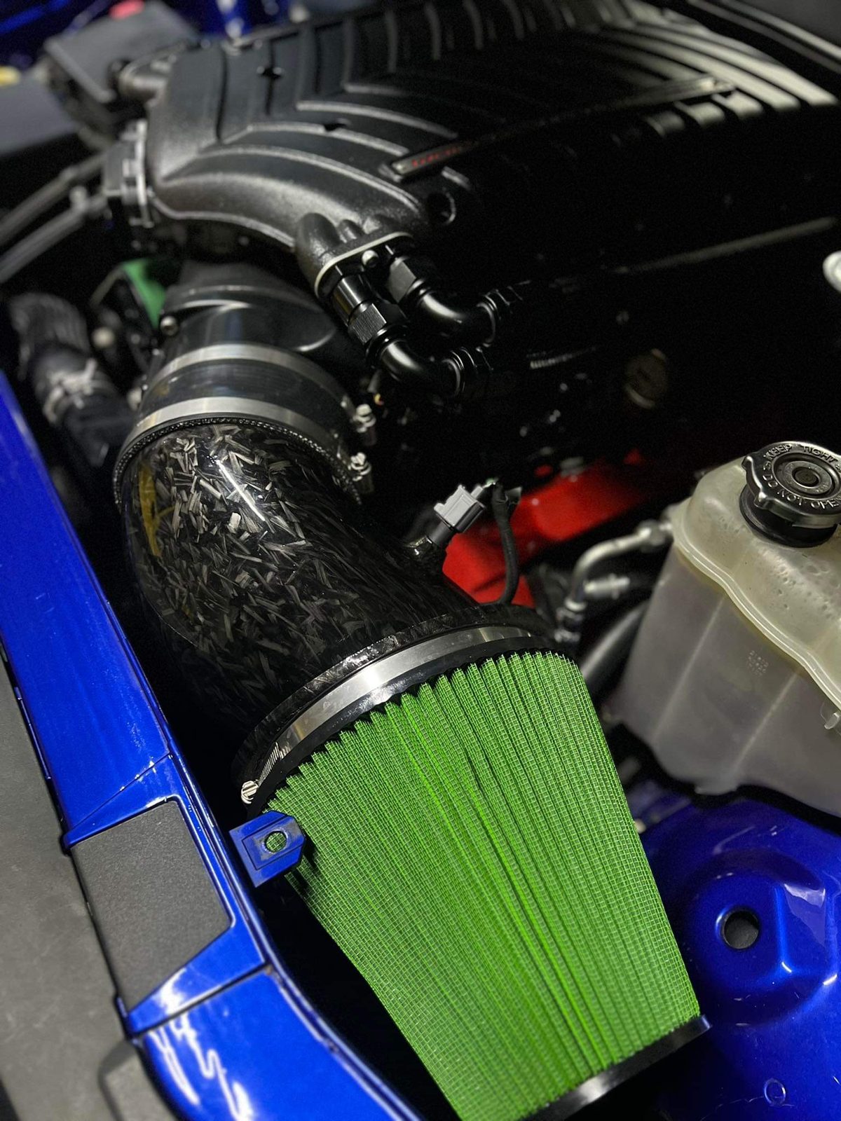 Green cone filter and carbon intake tube in a blue engine bay